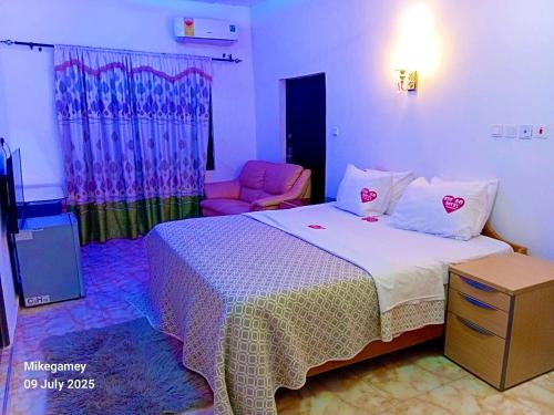 a bedroom with a large bed and a chair at Odo So Royal Hotel in Oko Sombo