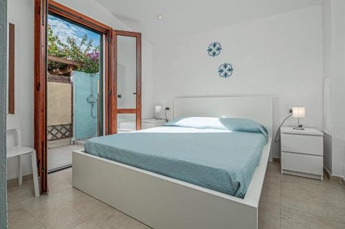 a white bedroom with a bed and a balcony at Villa Poldina in Budoni