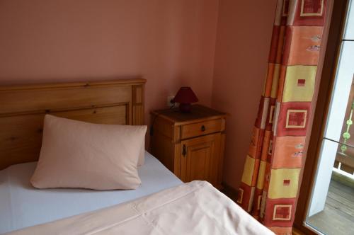 a bedroom with a bed with a white pillow and a window at Apartmány U Vaců in Železná Ruda