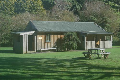 a wooden cabin with a picnic table in a field at Egmont Eco Leisure Park & Backpackers in New Plymouth