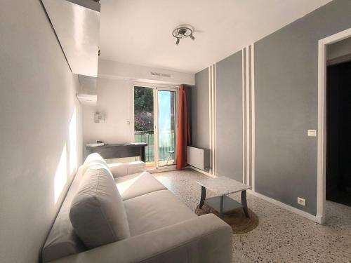 un salon avec un canapé blanc et une table dans l'établissement F1 - 8MIN DE LA PLAGE - 5MIN TRAMWAY, à Nice