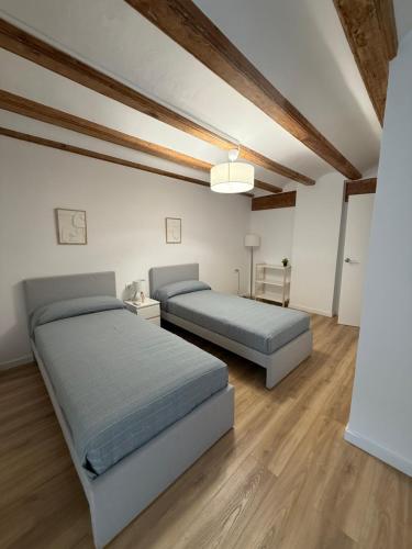 two beds in a room with wooden ceilings and wooden floors at K&A Apartments in Valencia