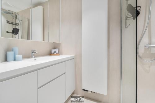 een witte badkamer met een wastafel en een douche bij Newport 3 - luxury apartment with side sea view in Nieuwpoort