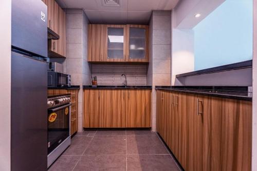 a large kitchen with wooden cabinets and a sink at Saadiyat Luxury Escape Walk to Beach & Museum in Abu Dhabi