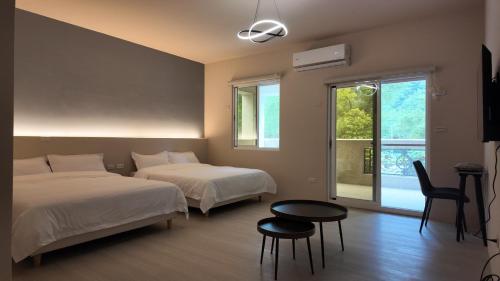 a bedroom with two beds and a table and a window at 樹海翠湖 in T'ung-ko