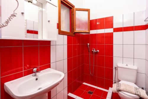 a red and white bathroom with a sink and a toilet at Motivo in Kastron