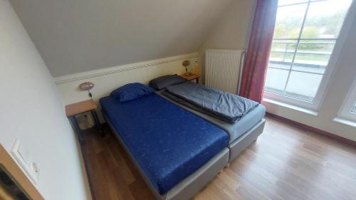 ein Schlafzimmer mit einem Bett mit blauen Laken und einem Fenster in der Unterkunft Haus am Golfplatz Cochem Mosel in Ediger-Eller