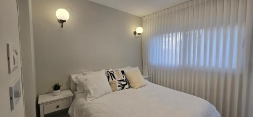 a bedroom with a bed with white sheets and pillows at GoldSea - Boutique Seafront Studio in Nahariyya