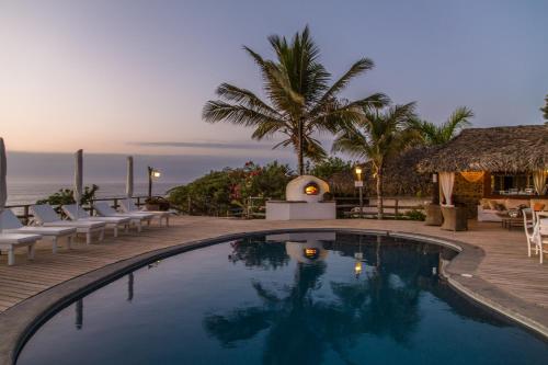 una piscina en un complejo con sillas y el océano en Villas del Mar Máncora, en Máncora