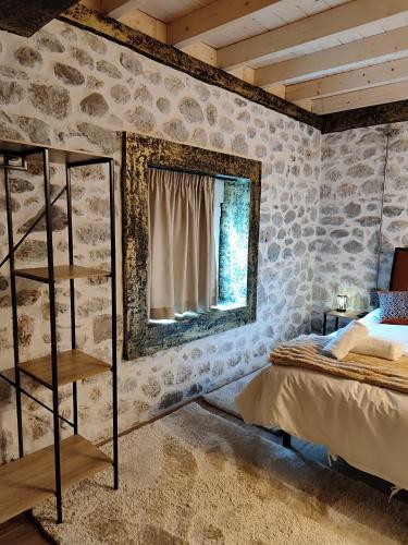 a bedroom with a stone wall with a mirror and a bed at Tommy's Guest House in Konitsa