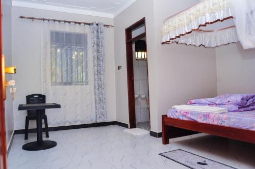 a bedroom with a bed and a table and a window at Shamo Inn And Lounge Mukono in Mukono