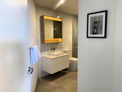 a bathroom with a sink and a toilet and a mirror at MERCER APARMENTS 2 Bedroom Apartment with Bay Views on the Geelong Waterfront - 609 in Geelong