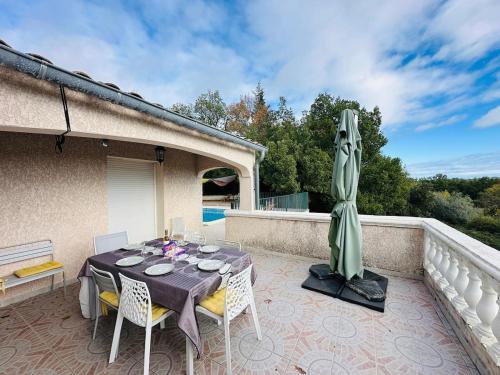 Una mesa y sillas en un patio con sombrilla. en Villa du sud avec piscine et jardin, en Saint-Christol-lès-Alès