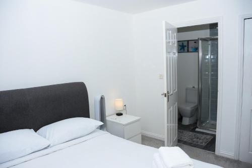 een slaapkamer met een bed en een badkamer met een douche bij Peterborough Haven: 3BD Family Home Retreat in Peterborough