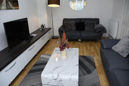 ein Wohnzimmer mit Fernseher und Tisch in der Unterkunft Peterborough Haven: 3BD Family Home Retreat in Peterborough