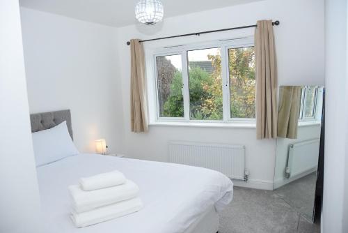 een witte slaapkamer met een bed en een raam bij Peterborough Haven: 3BD Family Home Retreat in Peterborough