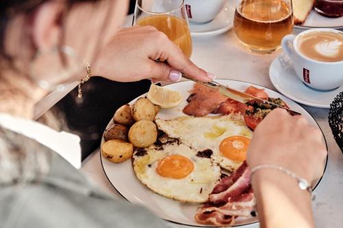 una mujer sentada en una mesa con un plato de comida para el desayuno en Crowne Plaza - Marseille Le Dôme, en Marsella