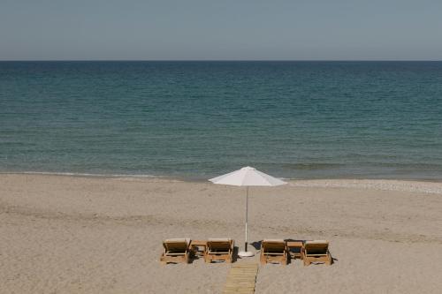 three chairs and an umbrella on the beach at Costel BeachFront Residence, BBQ & Private Sunbeds, By ThinkVilla in Fodele