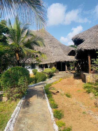 un camino frente a un edificio con techos de paja en Casuarina road 2 bedroom villa, en Malindi