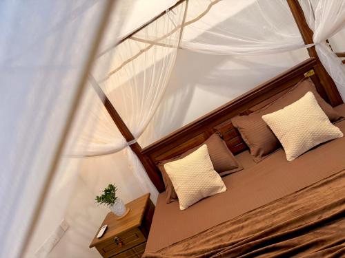 a bedroom with a canopy bed with pillows and a table at Sasmika Villa Surf and Yoga Hostel in Weligama