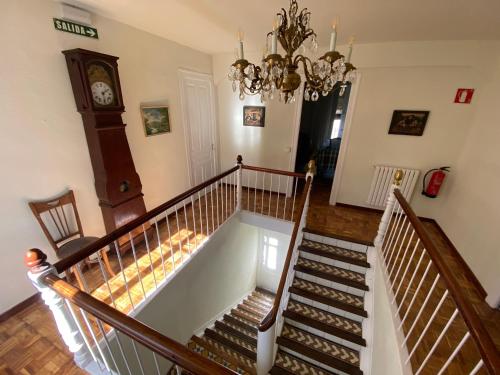 a room with a staircase with a clock and a chandelier at Casa Rural Masión de Egüés in Elcano