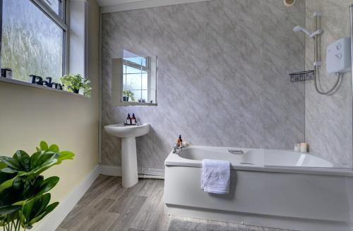 a bathroom with a white tub and a sink at 5 bedrooms, sleeps up to 16, secure parking space & comfort in Skegby