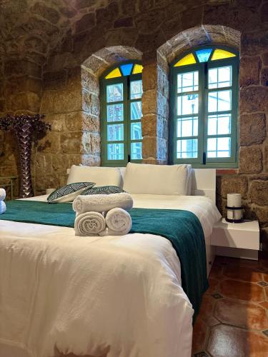 two beds in a room with two windows at Bab El Mina guest house Byblos port jbeil in Jbeil