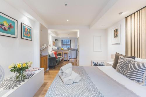a white bedroom with a bed and a living room at Compact & Bijou Chelsea Studio in London