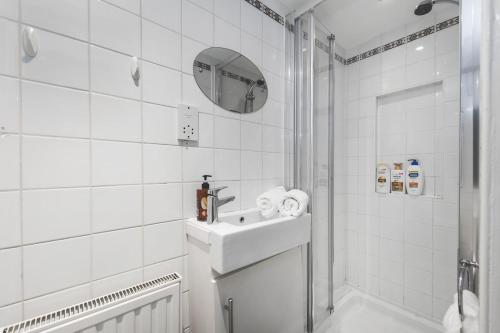 a white bathroom with a sink and a shower at Compact & Bijou Chelsea Studio in London