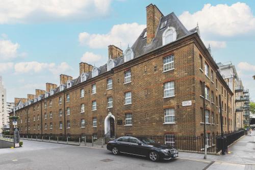 a black car parked in front of a large brick building at Compact & Bijou Chelsea Studio in London