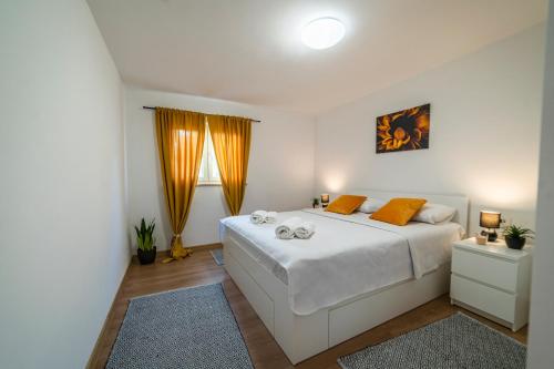 a white bedroom with a large white bed with orange pillows at Holiday house Solis in Rab