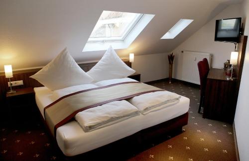 ein Schlafzimmer mit einem Bett mit weißen Kissen und einem Fenster in der Unterkunft Hotel Rothkamp in Frechen