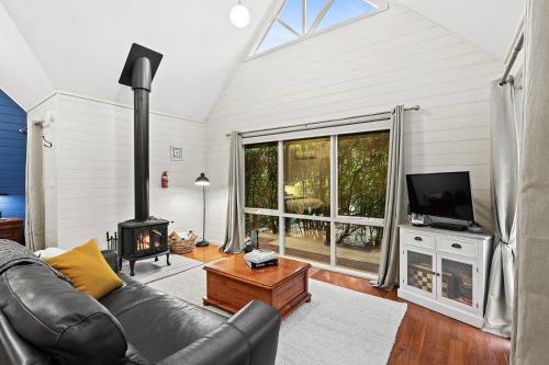 a living room with a leather couch and a fireplace at Two Truffles Cottage Accommodation in Yarra Glen