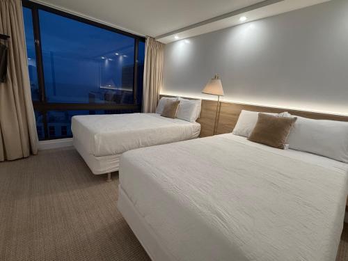 ホノルルにあるNewly renovated luxury, modern style Waikiki Sunset Hotel Ocean view Freeparkingのベッドが2つと窓があるホテルの部屋