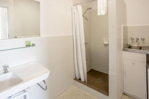 a white bathroom with a shower and a sink at Nightcap at Emerald Star Hotel in Emerald