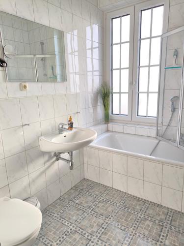 a bathroom with a sink and a tub and a toilet at Golf- & Landhotel am alten Deich in Büsum