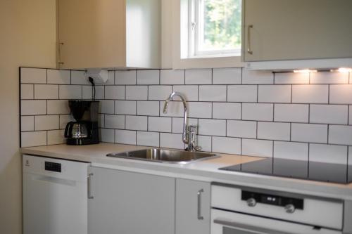 een keuken met een wastafel en een witte tegelmuur bij Lilla Brattön in Myggenäs