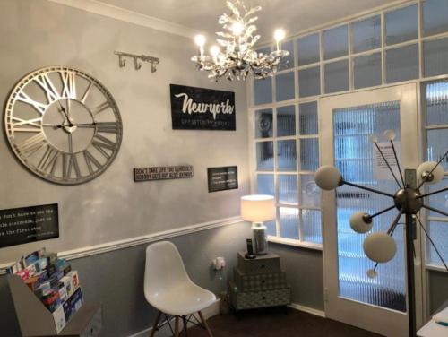 a room with a clock on the wall and a chair at The Georgian Guesthouse in Alnwick