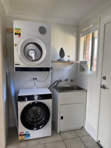 a laundry room with a washing machine and a sink at Cozy Stay in Forster in Forster