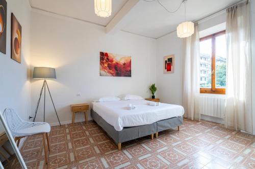 a white bedroom with a bed and a chair at Firenze Center - 9' to Duomo & Uffizi - AC, Wifi in Florence