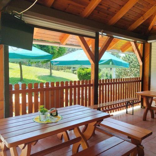 a wooden deck with a picnic table and blue umbrellas at Resort Koloděje - oranžový dům in Koloděje nad Lužnicí