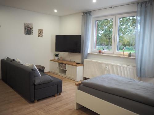 a living room with a couch and a tv and a chair at Ferienwohnung am Mühlenweg in Petershagen