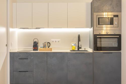 une cuisine avec des armoires blanches et un micro-ondes dans l'établissement Dobo Málaga Perchel, à Malaga