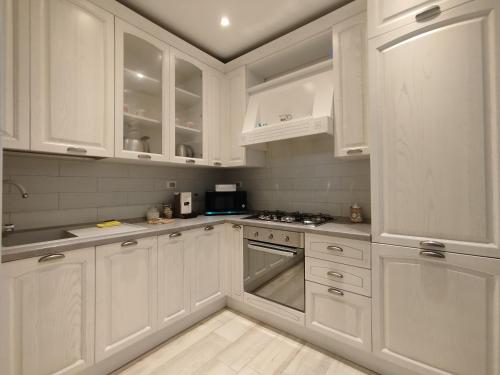 a white kitchen with white cabinets and a stove at Appartamento al parco con parcheggio gratuito in Orbetello