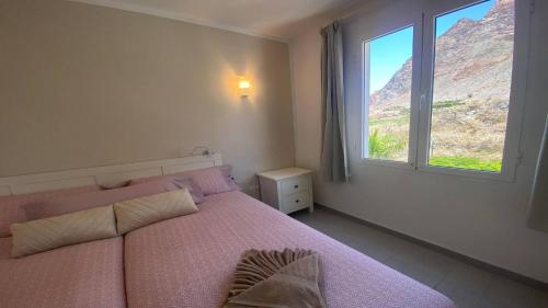 1 dormitorio con cama rosa y ventana en Apt. El Guirre Nº 6, en Playa Calera