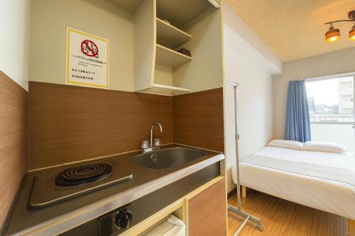 a small kitchen with a sink and a bed at Kurarisu Hakata クラリス博多 in Fukuoka