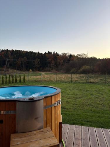 a hot tub on a wooden deck with a field at Bieszczadzki Relaks - domki z prywatną strefą SPA in Uherce Mineralne (7)
