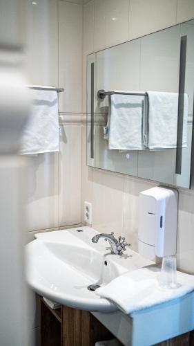 a bathroom with a sink and a mirror and towels at Hotel Beemster in Middenbeemster