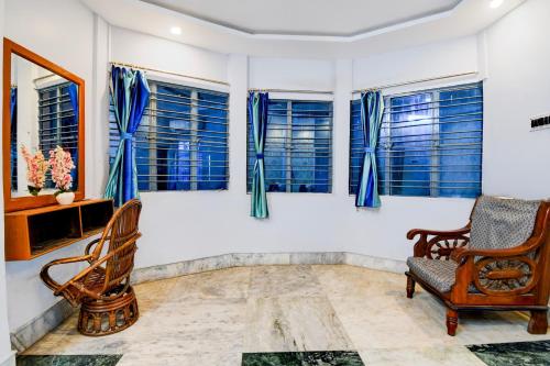 a room with chairs and windows with blue curtains at Super Hotel O Shalimar Railway Junction Formerly Tanima Villa 2 in Howrah