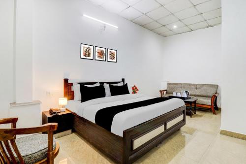 Un dormitorio con una cama grande y una silla. en Super Hotel O Dehradun Central Railway Junction Formerly Bhagwan Guest House, en Dehradun